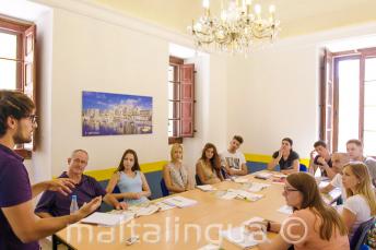 Opettaja puhuu luokalle, joka on täynnä englannin kielen opiskelijoita.